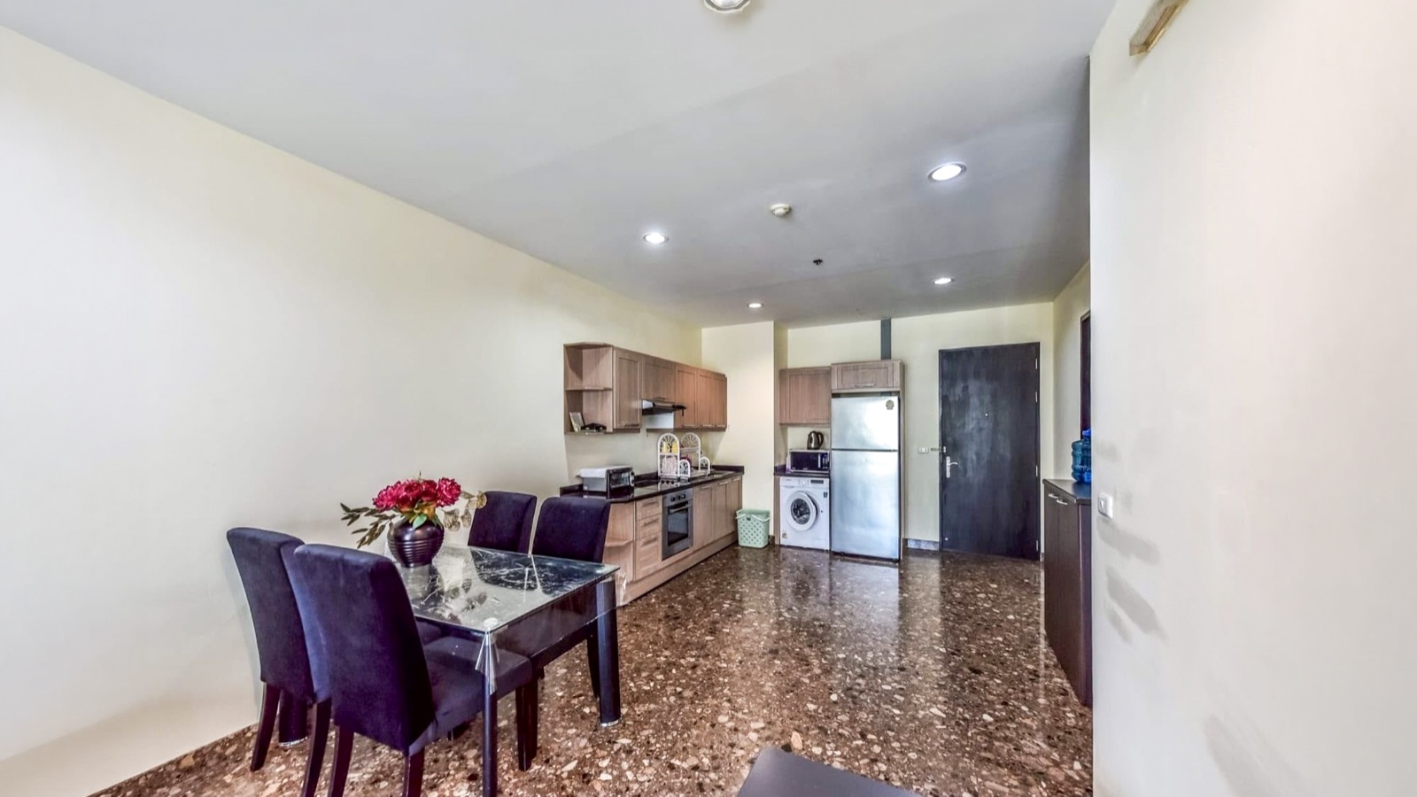 Dining table and fitted kitchen viewed toward the condominium entrance
