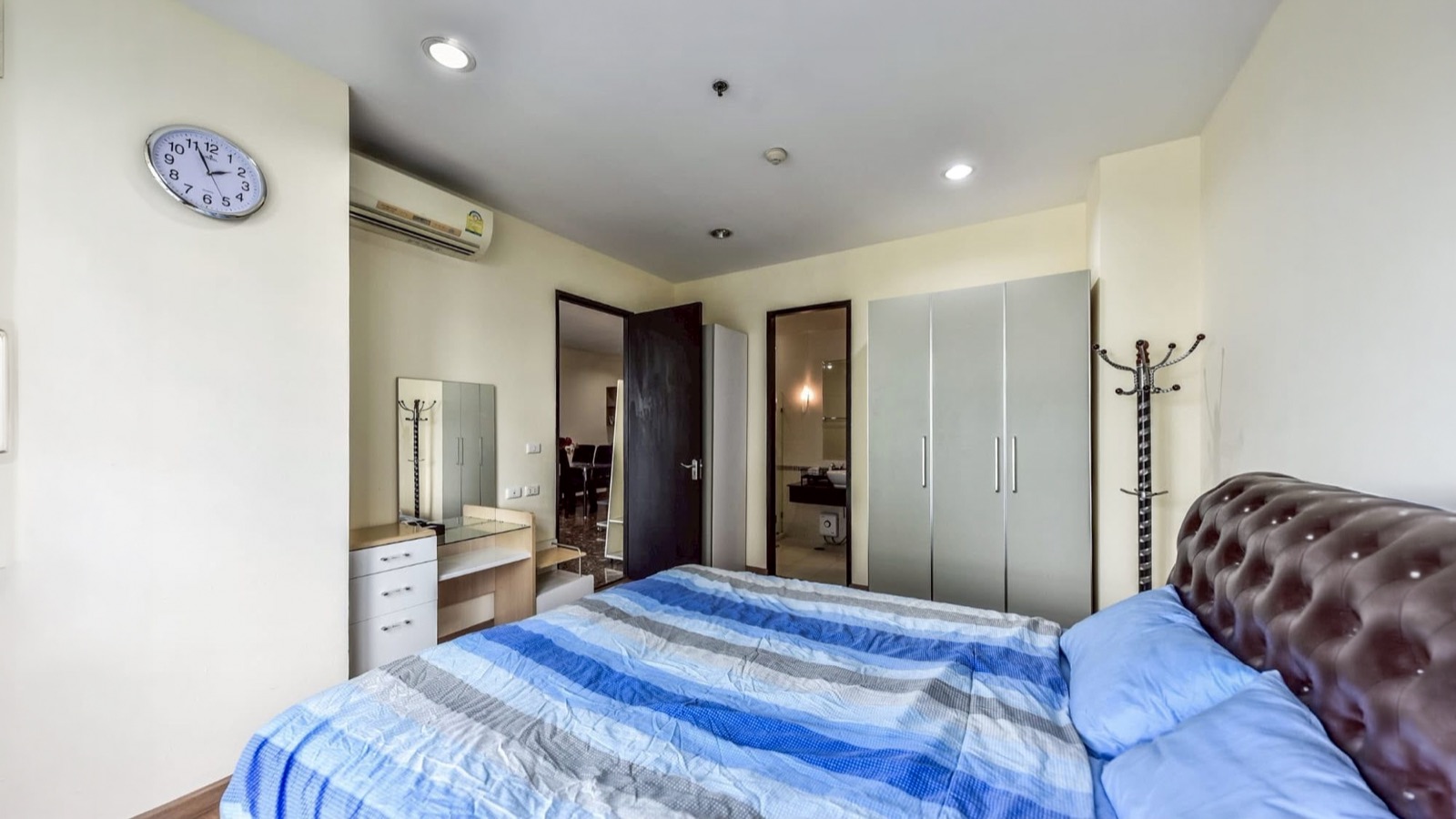 Main bedroom showing the bed, vanity, wardrobe, and bathroom doorway