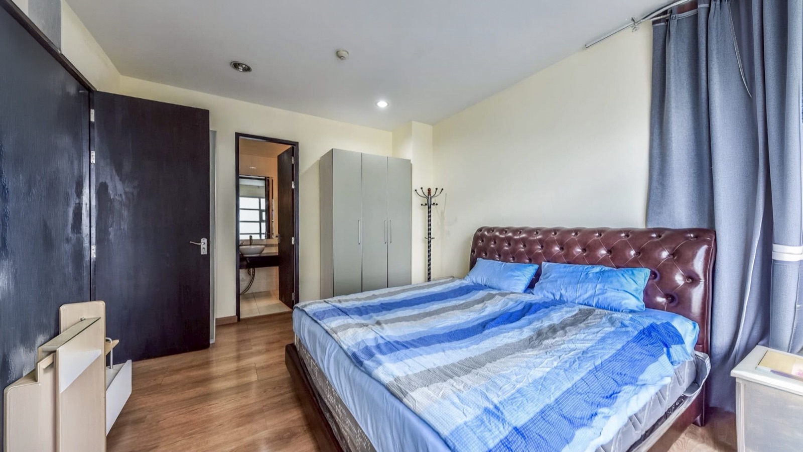 Main bedroom with bed, wardrobe, window curtains, and bathroom doorway