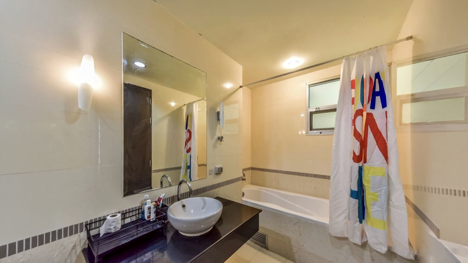 Bathroom with bathtub, vessel basin, large mirror, and window